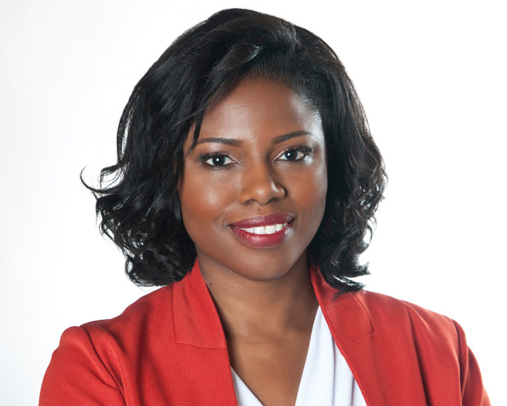 Judy smiling into the camera wearing a red blazer with a white shirt underneath. Behind her is a white background.