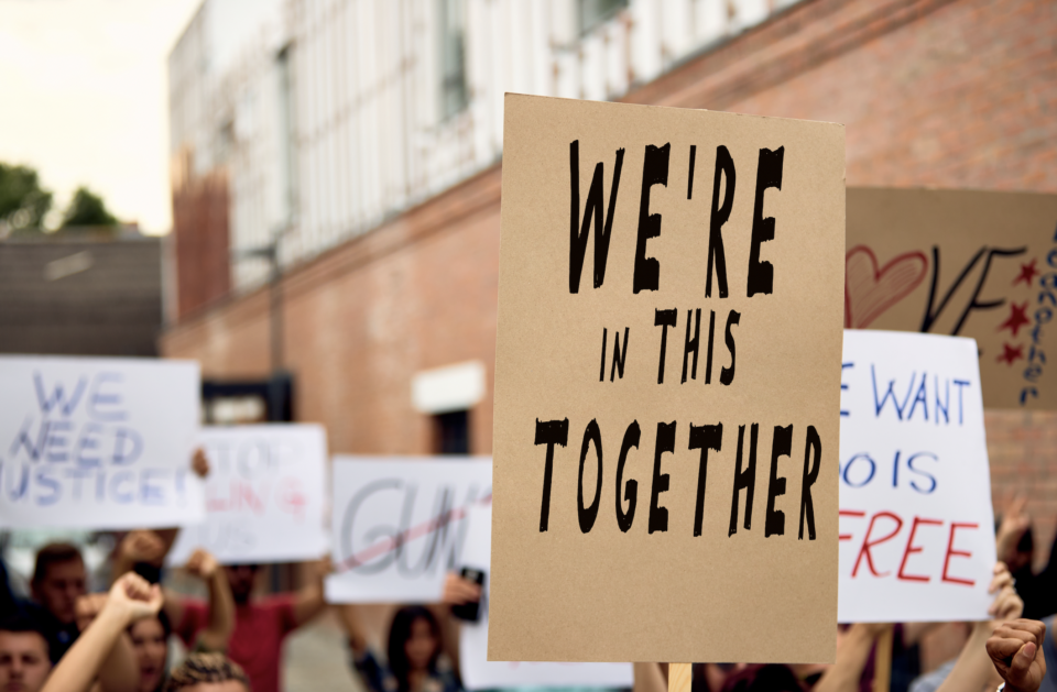 a sign reading "we're in this together" at a protest