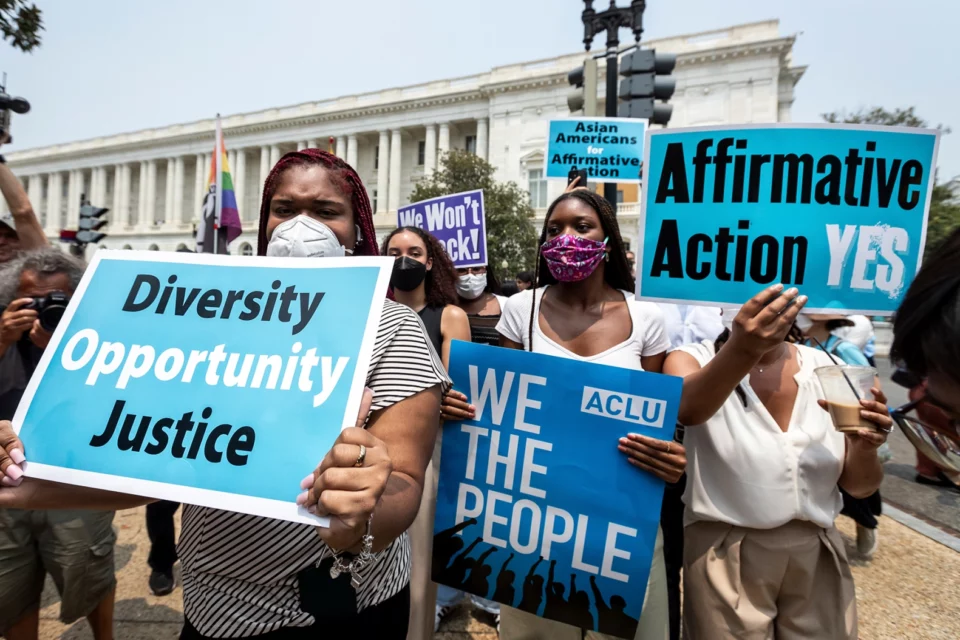 Masked protestors outside of the Supreme Court hold up sings in support of affirmative action.